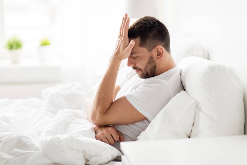 mężczyzna na łóżku martwi się swoimi problemami z erekcją wywołanymi stresem
